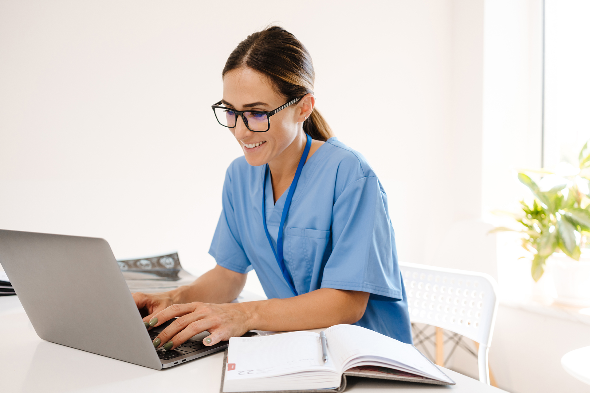 doctor working on a laptop from her office to collaborate with healthcare colleagues remotely