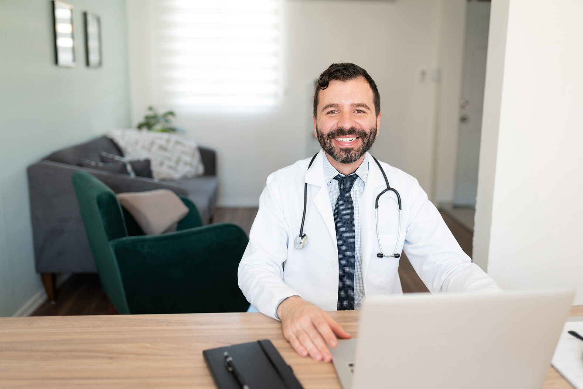A doctor working from home on his laptop to speak with colleagues and patients