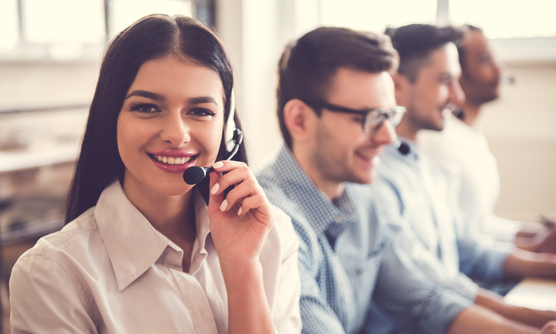 Smiling customer support team using customer support software and wearing headsets